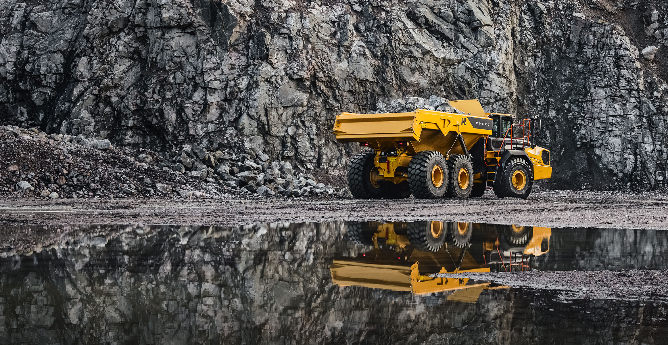 A Volvo ADT hauling a load next to water in a quarry.
