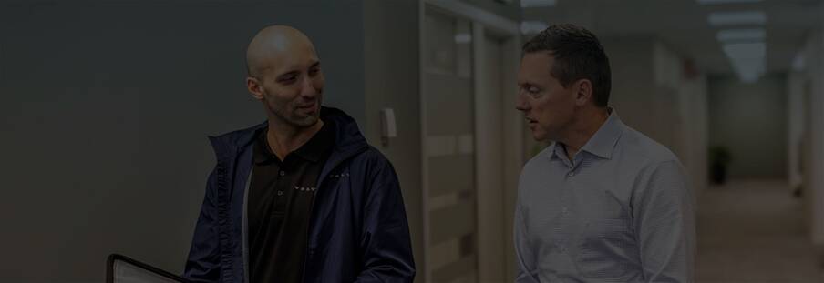 Two men walking down a hallway talking about the Volvo Smart Commercial Account.