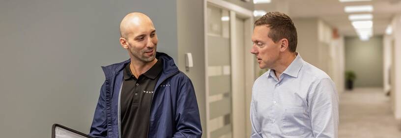 Two men walking down a hallway talking about the Volvo Smart Commercial Account.