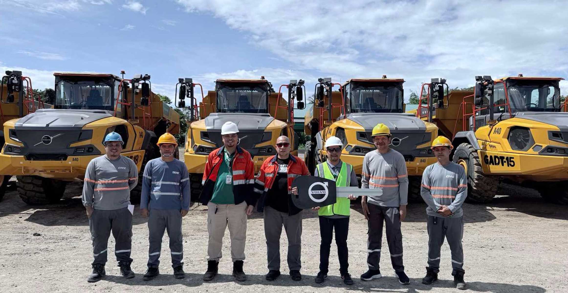 John Gerald Nofuente, the Greenstone Resources Corporation, and the Civic Merchandising team in front of the Eight New Generation A40 articulated haulers