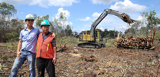 Owner of the Prima Kas Lestari company, Mansudin (right), poses in front of a working Volvo excavator with his son, Nico Jonathan