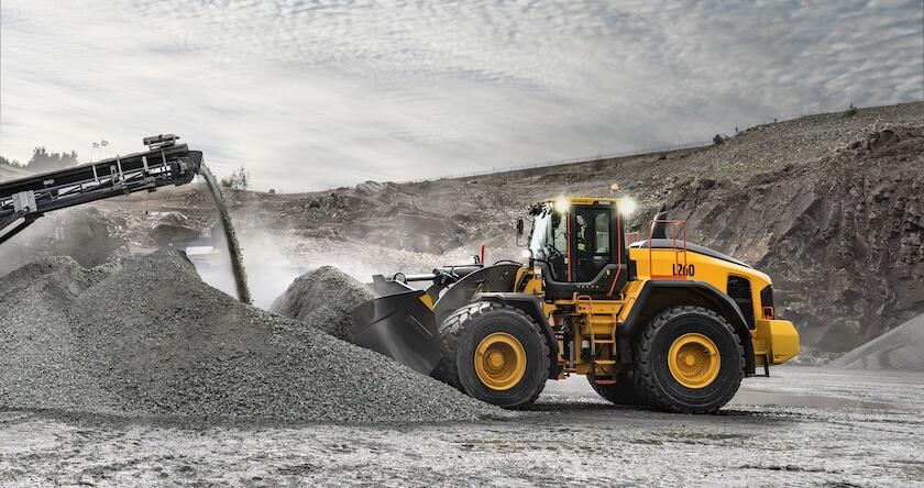 A Volvo L260 wheel loader moving gravel at the end of a crusher in an aggregate production facility.